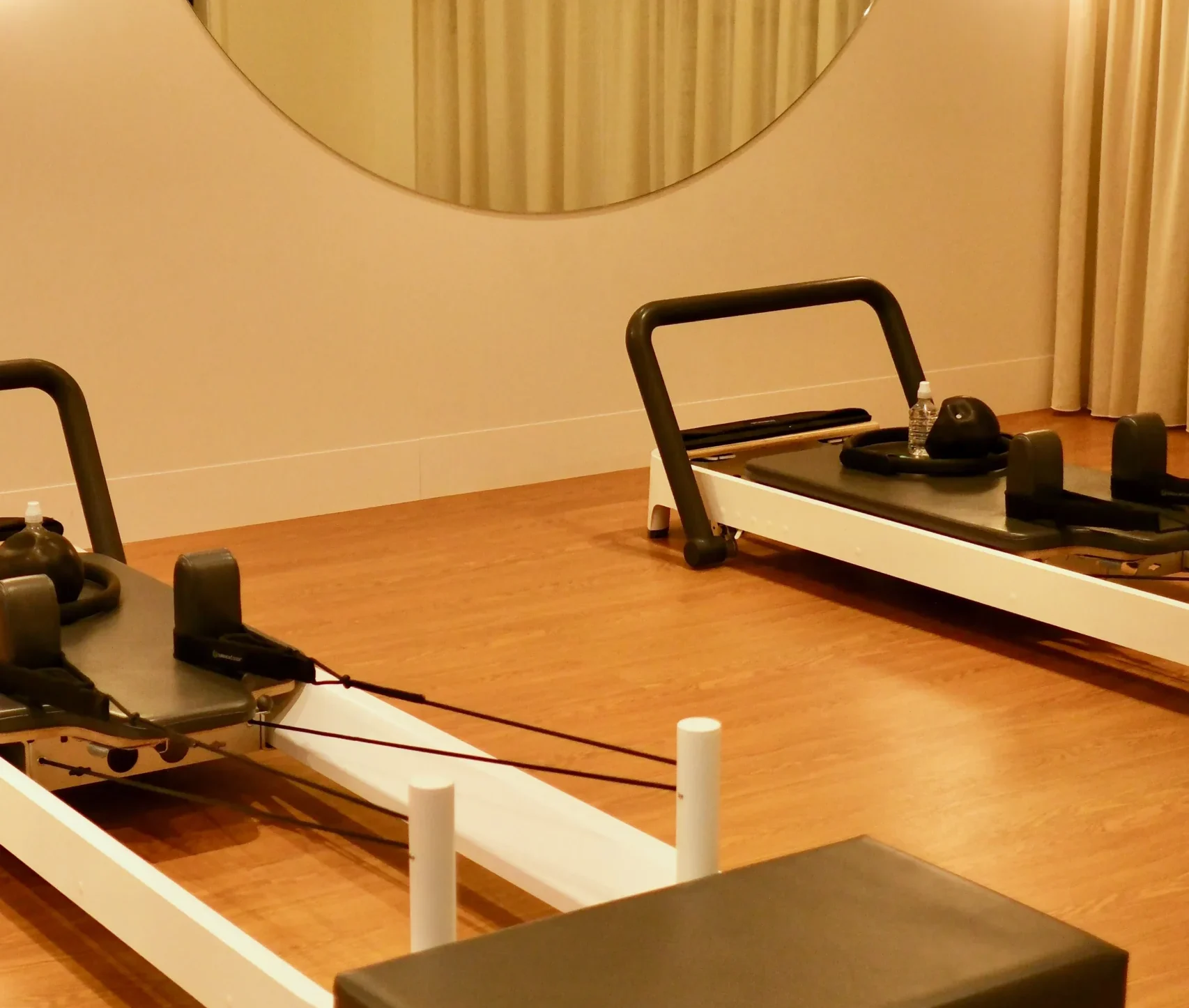 Two pilates reformer machines positioned side by side in a modern fitness studio.